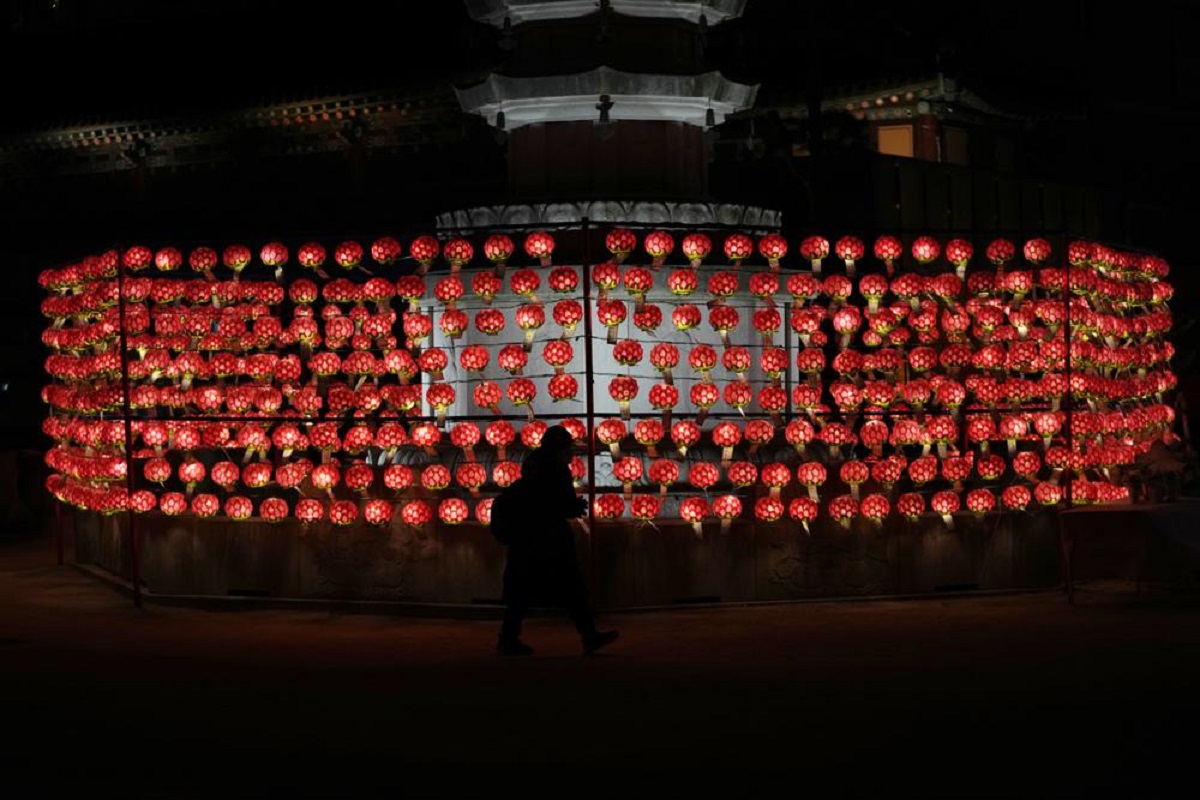 Một phụ nữ cầu nguyện trước những chiếc đèn lồng vào đêm giao thừa tại đền Jogye ở Seoul, Hàn Quốc, ngày 31/12/2021. (Ảnh: AP) 