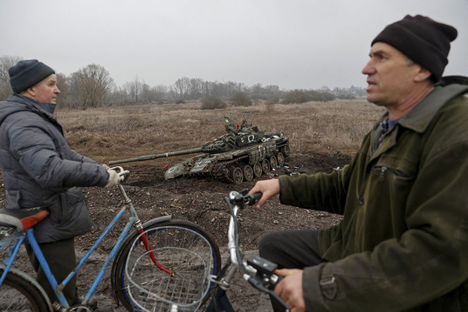 Cư dân địa phương đi gần một xe tăng bị bỏ lại tại làng Nova Basan, vùng Chernihiv, Ukraine ngày 1/4/2022. Ảnh: Reuters 