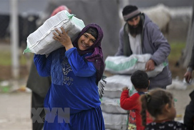 Người tị nạn Syria nhận hàng viện trợ. (Ảnh: AFP/TTXVN)